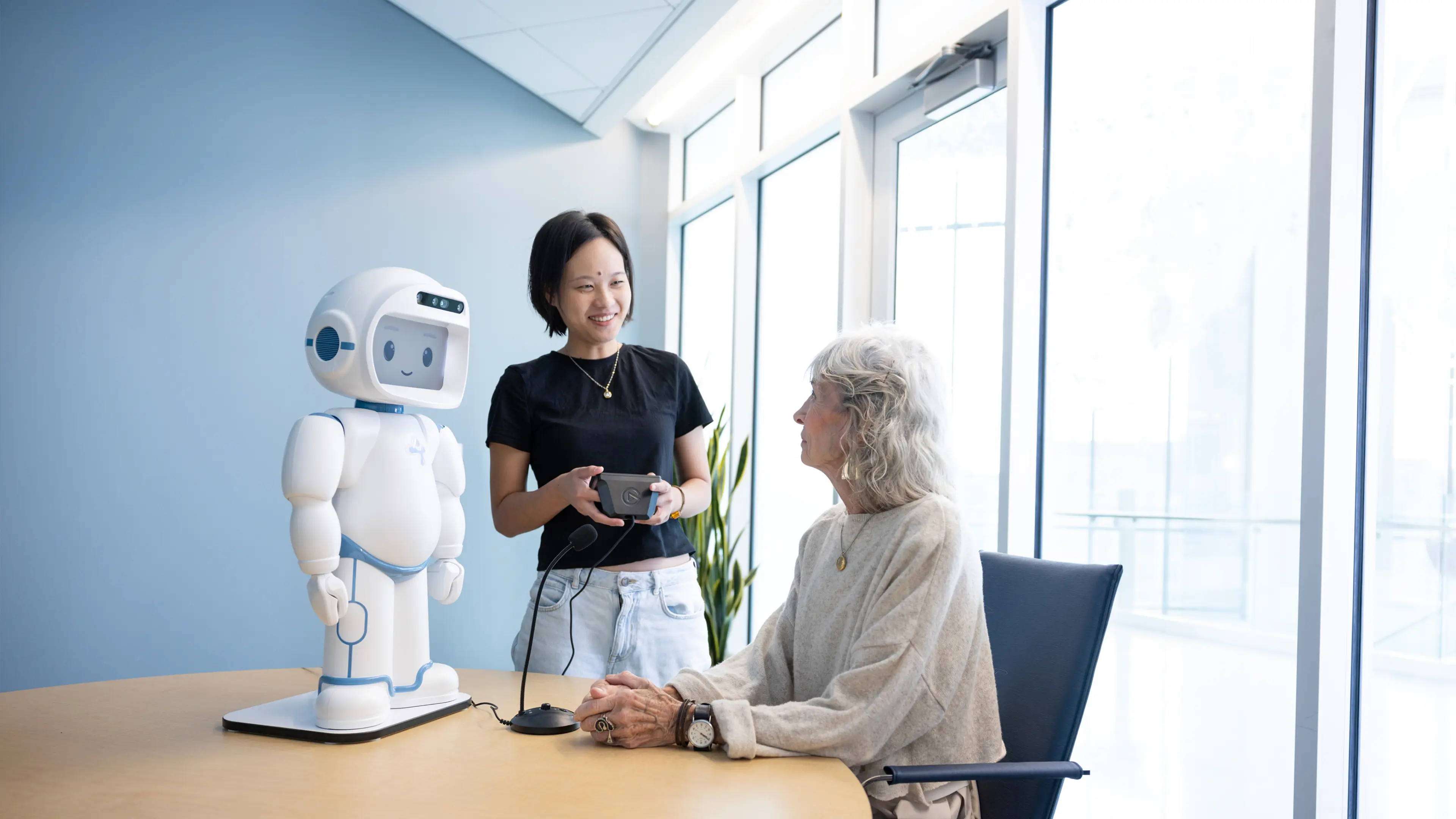 Two people operating a small humanoid robot standing on a table.