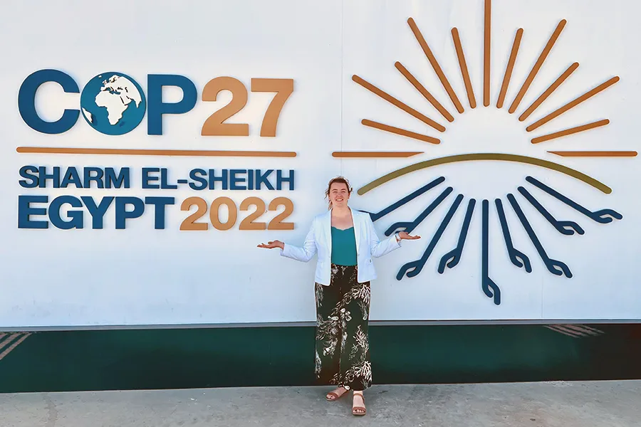 Students stand in front of a wall with the conference name on it.