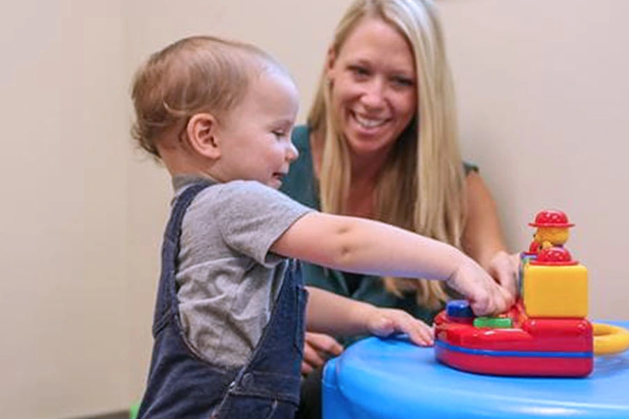 A very young autistic child plays while a researcher watches.