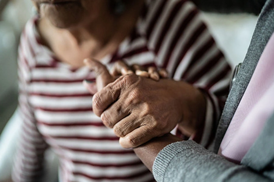 A caregiver holds hands with a patient.