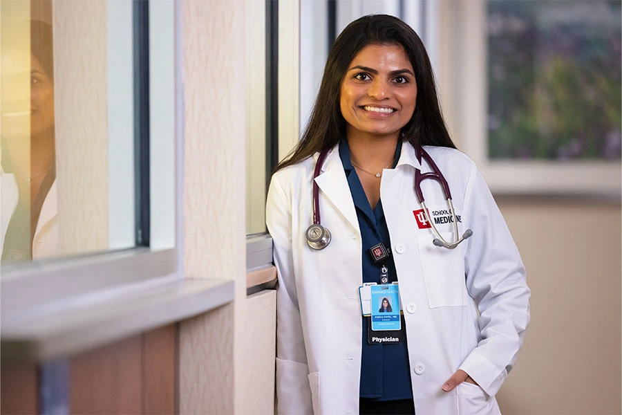 A young IU doctor in her white coat smiles at the camera.